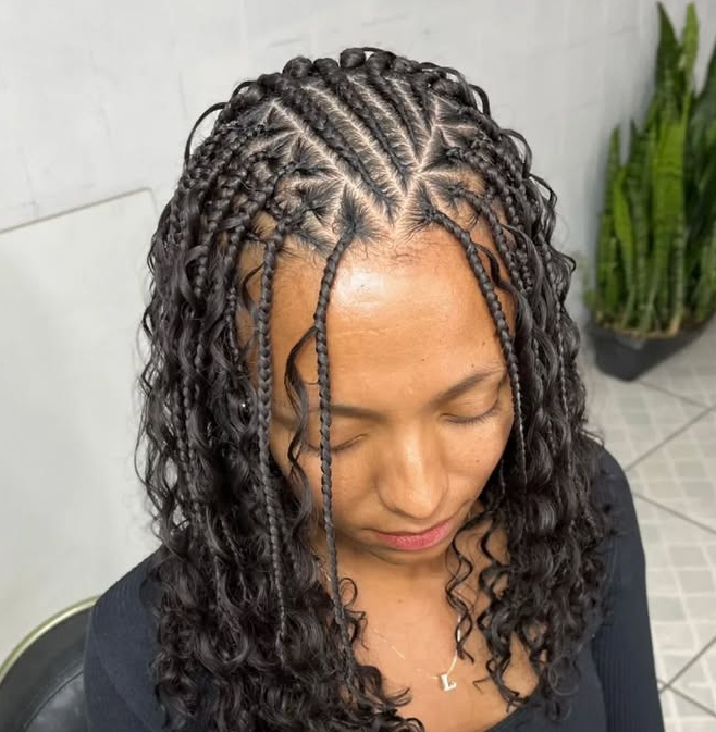 Close-up of a woman's head showcasing a flip-over Fulani braids hairstyle with cornrows and curly ends.
