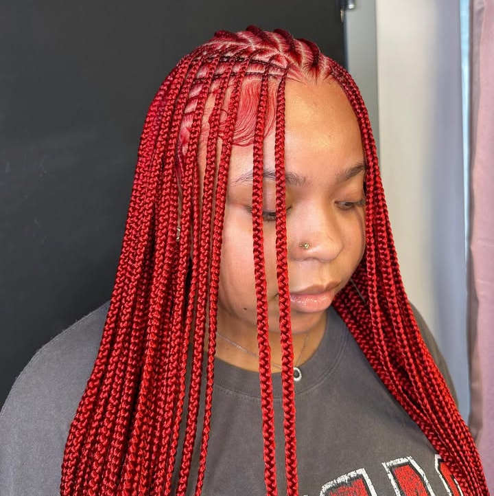 A close-up of a person with long red flip-over Fulani braids, showcasing the intricate braided pattern and hair texture.