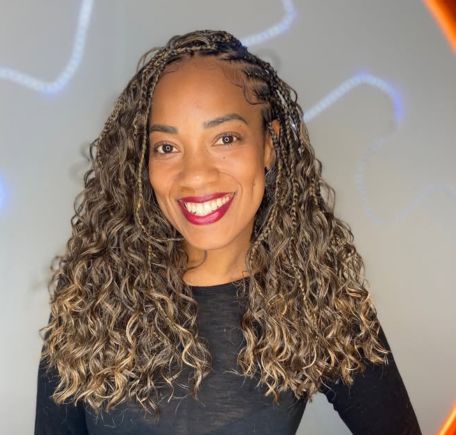 A woman with curly hair showcases an elegant flip-over Fulani braids hairstyle, smiling at the camera.
