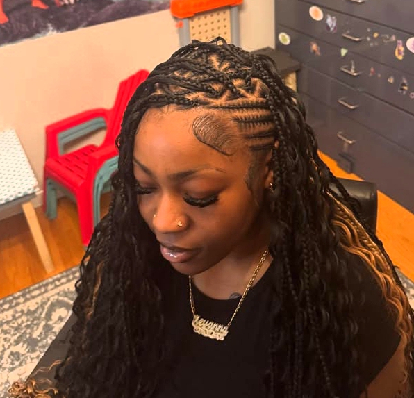 A person with flip-over Fulani braids hairstyle featuring knotless braids and sleek cornrows, looking down while showing detailed hair design.