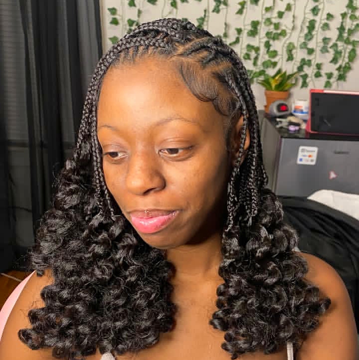 A woman showcasing a flip-over Fulani braids hairstyle with curly ends, featuring a blend of knotless braids and cornrows.