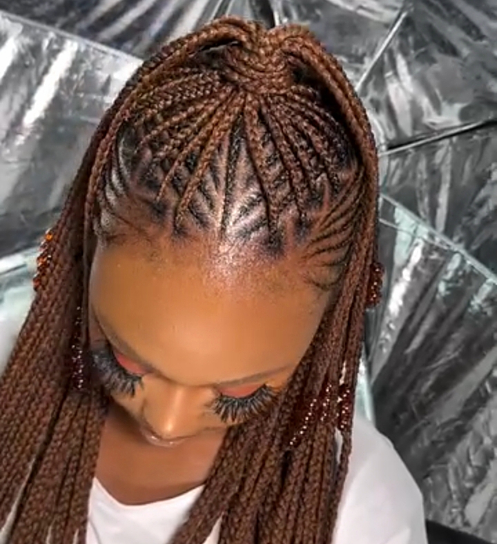 A close-up of a woman showing a flip-over Fulani braids hairstyle, featuring intricate cornrows at the top and loose braids that can be styled in various ways.