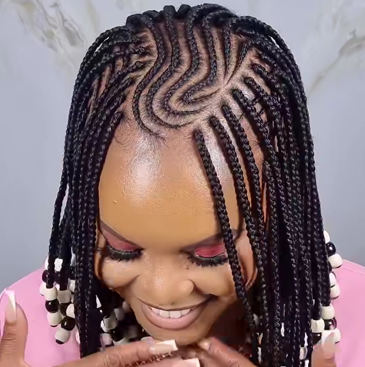 Close-up of a woman showcasing a stylish flip-over Fulani braids hairstyle with intricate cornrow patterns and decorative beads.