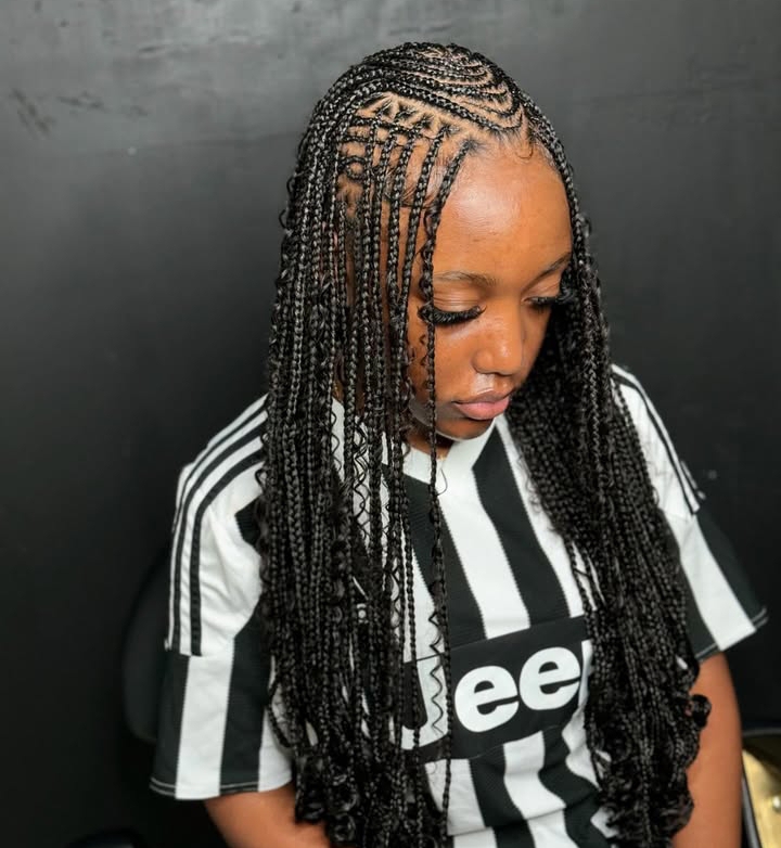 Close-up of a woman with flip-over Fulani braids styled in a combination of knotless braids and cornrows, wearing a black and white striped shirt.