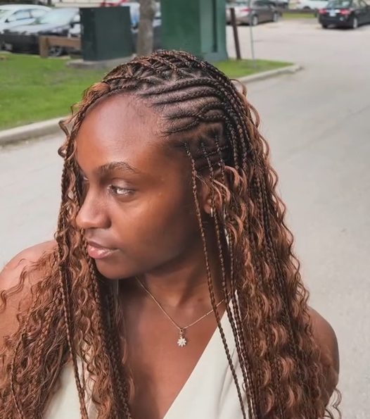 A woman with flip-over Fulani braids hairstyle, featuring knotless braids with a mix of cornrows, looking to the side outdoors.
